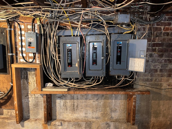 Before photo of commercial electrical panel showing outdated wiring and equipment needing replacement